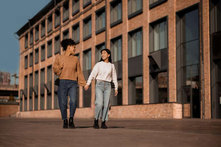 Two pretty girls walking and talking, feeling joyfulの写真素材