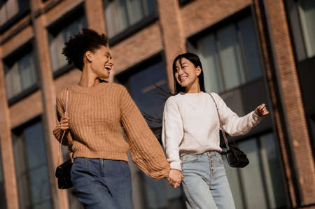 Two pretty girls walking and talking, feeling joyfulの写真素材