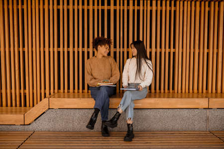 Two girls sitting on a bench and talkingの写真素材