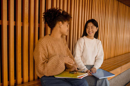 Two girls sitting on a bench and talkingの写真素材