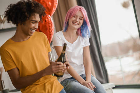 Young man opening a bottle of champagneの写真素材