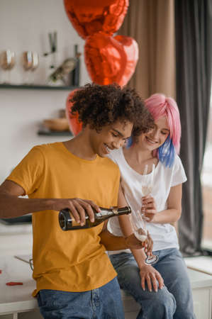 A smiling young man pouring champagne to his girlfriends glassの写真素材