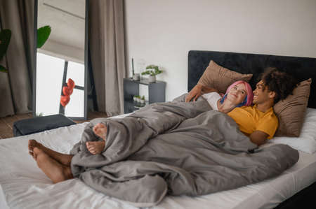 Young couple feeling comfortable and close while lying in bedの写真素材