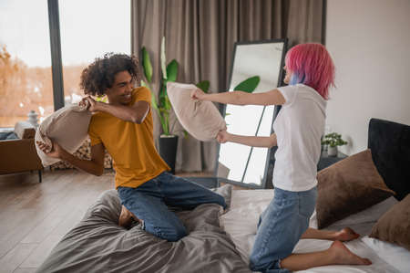Young couple having fun and fighting with pillowsの写真素材