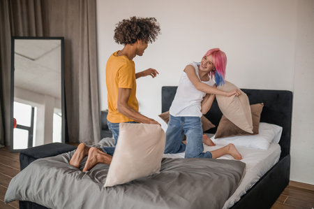 Young couple having fun and fighting with pillowsの写真素材