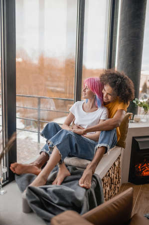 Young man and woman sitting in the chair hugging each otherの写真素材