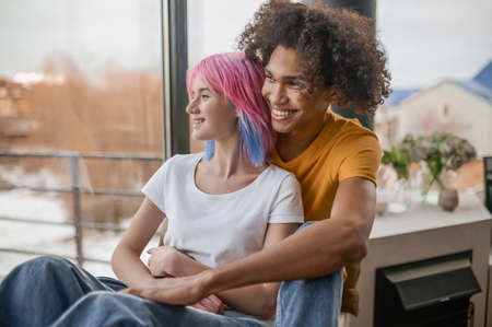 Young man and woman sitting in the chair hugging each otherの写真素材