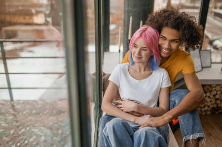 Young man and woman sitting in the chair hugging each otherの写真素材