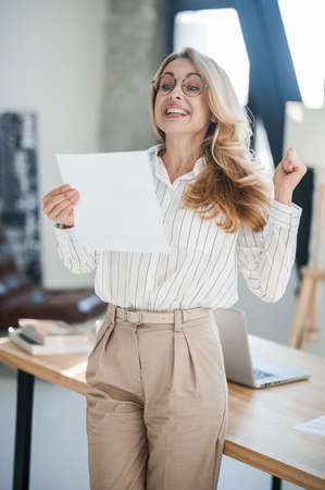 A blonde elegant woman in the offcie with documents in handsの写真素材