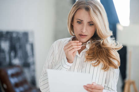 Blonde woman reading something and looking upsetの写真素材