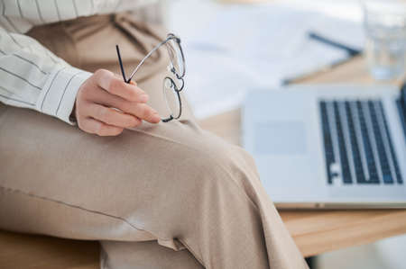 Close up picture of a woman in beige pants sitting on tableの写真素材