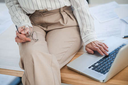 Close up picture of a woman in beige pants sitting on tableの写真素材