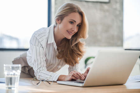A cute elegant woman in the office working on laptopの写真素材