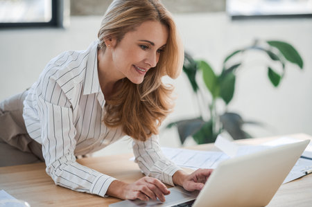 A cute elegant woman in the office working on laptopの写真素材