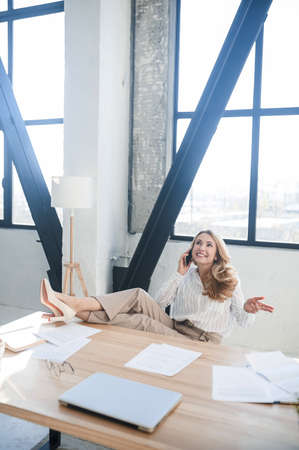 A blone businesswoman in her office talking on the phoneの写真素材