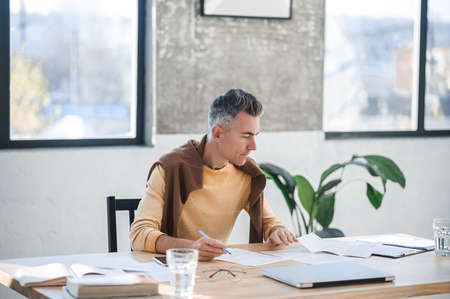 A dark-haired man sitting at the table and working with documentsの写真素材