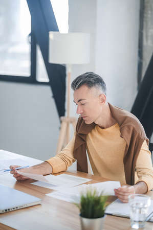 A dark-haired man sitting at the table and working with documentsの写真素材
