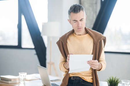 A man holding a document in hands and looking interestedの写真素材