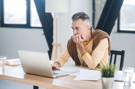 A man in casual clothes working in the office and looking involvedの写真素材
