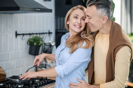 A couple hugging in the kitchen and looking happyの写真素材
