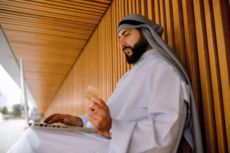 An arabian man in traditional clothing holding a credit cardの写真素材