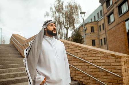 An arabian man in white traditional clothing on the stairsの写真素材