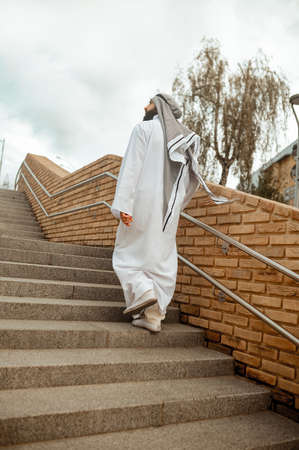 An arabian man in white traditional clothing on the stairsの写真素材
