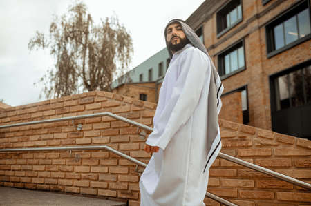 An arabian man in white traditional clothing on the stairsの写真素材