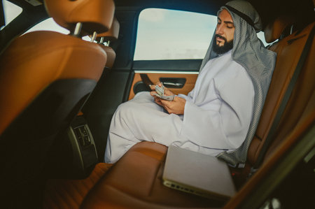 Saudi man in a traditional clothing in a car holding moneyの写真素材
