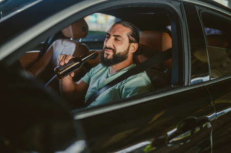 Young handsome dark-haired man driving a car and smilingの写真素材
