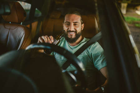 Young handsome dark-haired man driving a car and smilingの写真素材