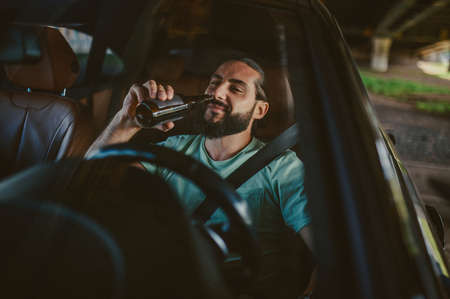 Young handsome dark-haired man driving a car and smilingの写真素材