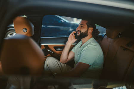 A handsome young man talking on the phone in a carの写真素材