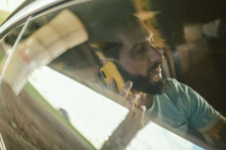 A handsome young man talking on the phone in a carの写真素材