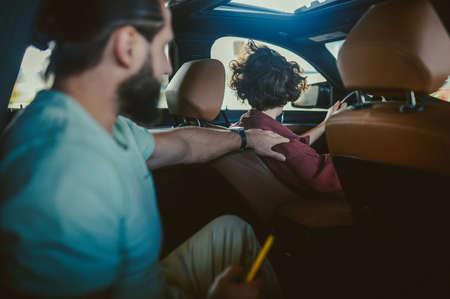 A young with a coffee cup sitting in a carの写真素材