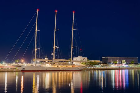 Colors of Tarragona port at night with beautiful moored yacht, summer Spain