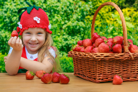 A funny little girl 4 years old with a basket of strawberriesの写真素材