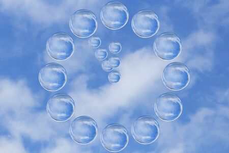 Many soap bubbles form a clock showing five minutes to twelve oclock against blue skyの写真素材