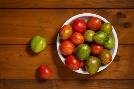 Colorful tomatoes in a bowl on the wooden tableの写真素材