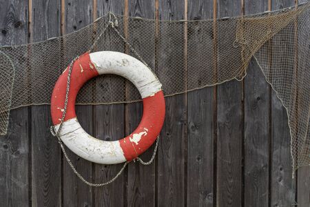 Old lifebelt and fishing net hanging on the wooden wallの写真素材