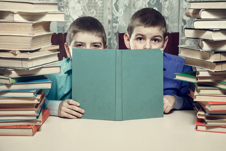 The boys are hiding behind the book. do not want to do homework