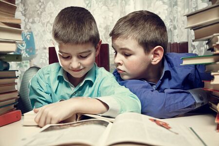 The boys at the table reading a book togetherの写真素材