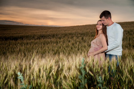 young parents in the evening on a wheat fieldの写真素材