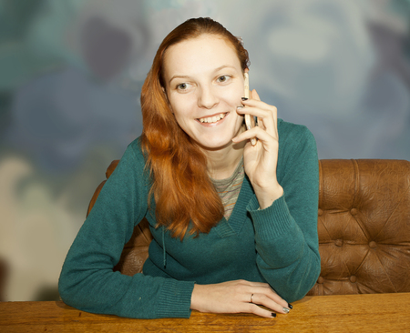 Young beautiful red-haired woman talking on a mobile phoneの写真素材