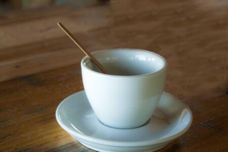 An empty coffee cup with a saucer and a stick stand on a tableの写真素材