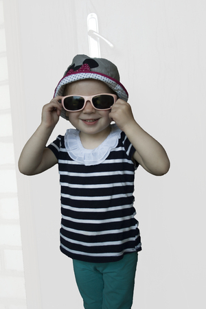 Little girl with sunglasses smiling against white backgroundの写真素材