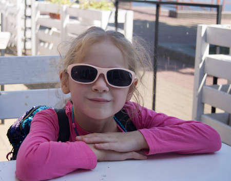girl in sunglasses sits at the tableの写真素材