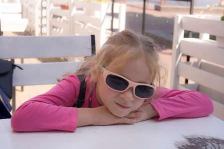 girl in sunglasses sits at the tableの写真素材