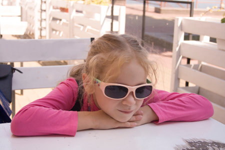 girl in sunglasses sits at the tableの写真素材