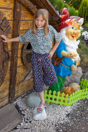 A little girl near a figure of a garden gnome.の写真素材